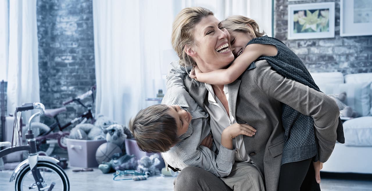 Frau lacht herzhaft und hält zwei Kinder im Arm. Vereinbarkeit von Beruf & Familie #Work-life-Balance